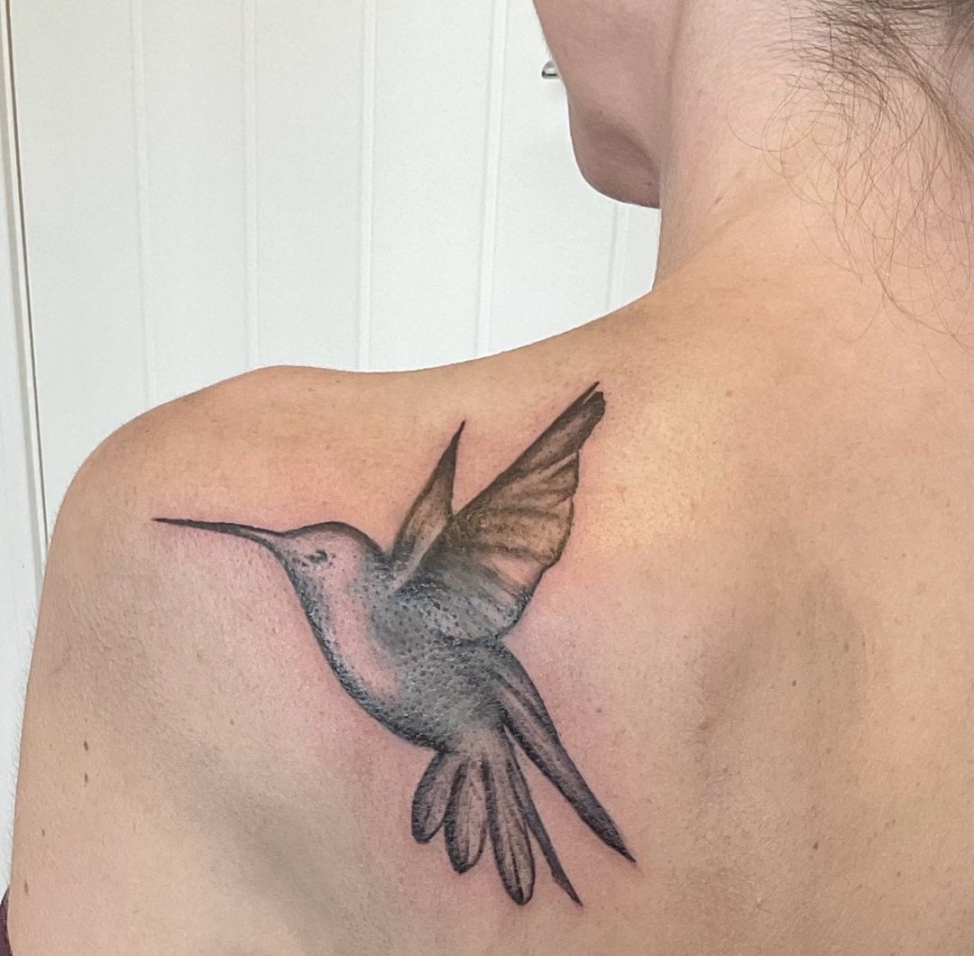 Tatuaje de colibrí con tinta negra en el hombro.