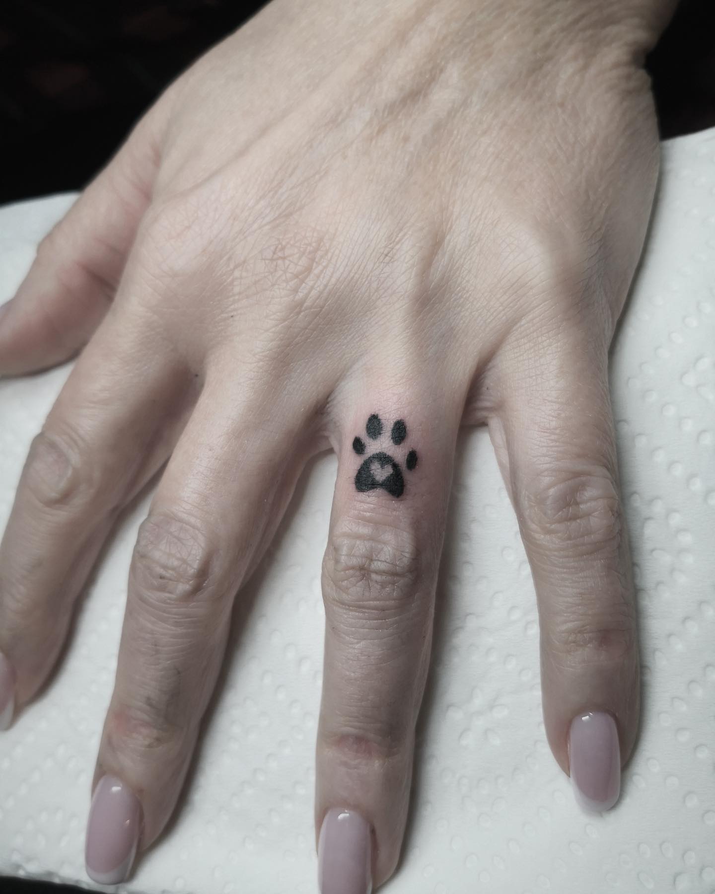 Tatuaje de huella de pata de mascota en el dedo
