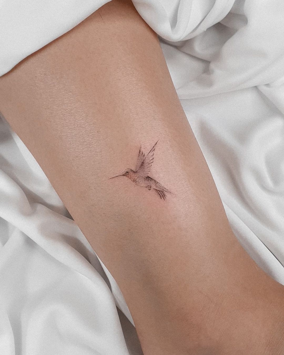 Tatuaje pequeño de colibrí de tinta negra.