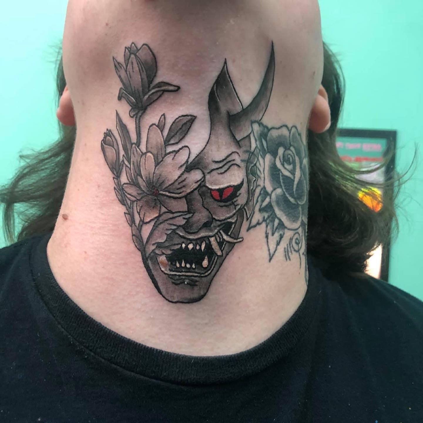 Tatuaje de máscara Oni floral en la garganta.
