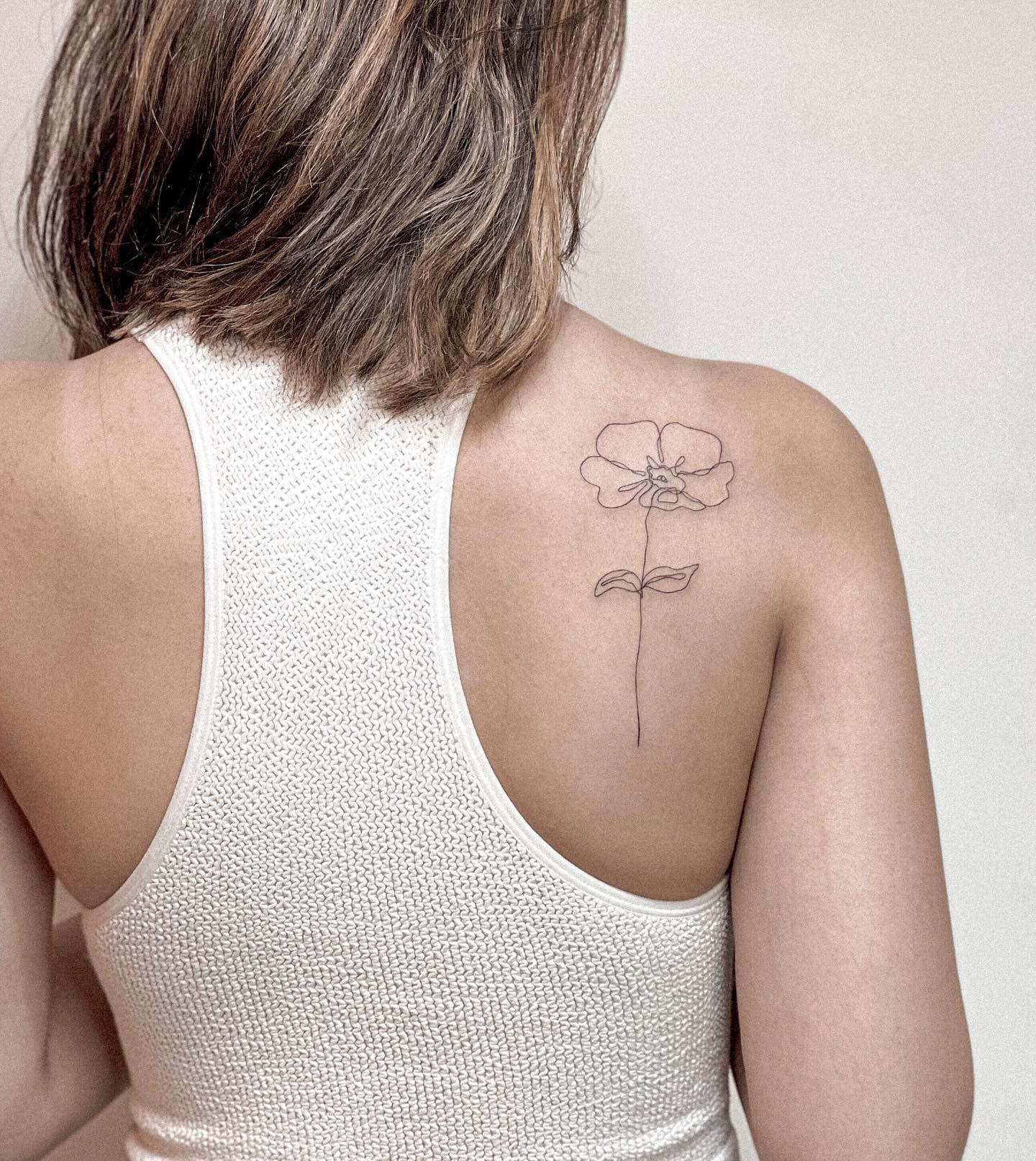 Tatuaje pequeño de flor en la espalda para mujeres.