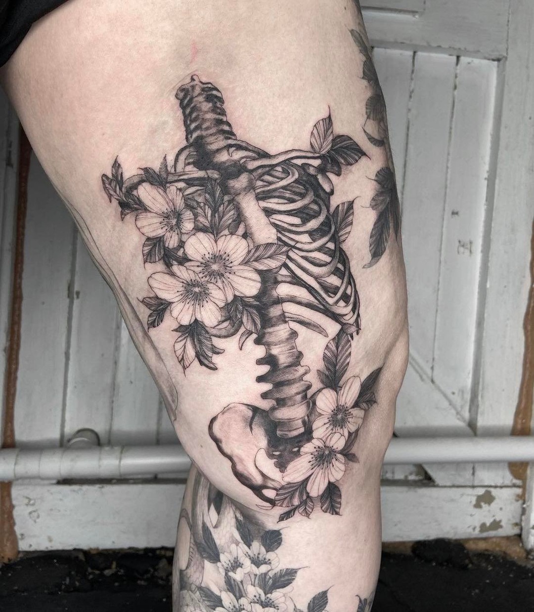 Tatuaje floral de esqueleto en el muslo para hombres.