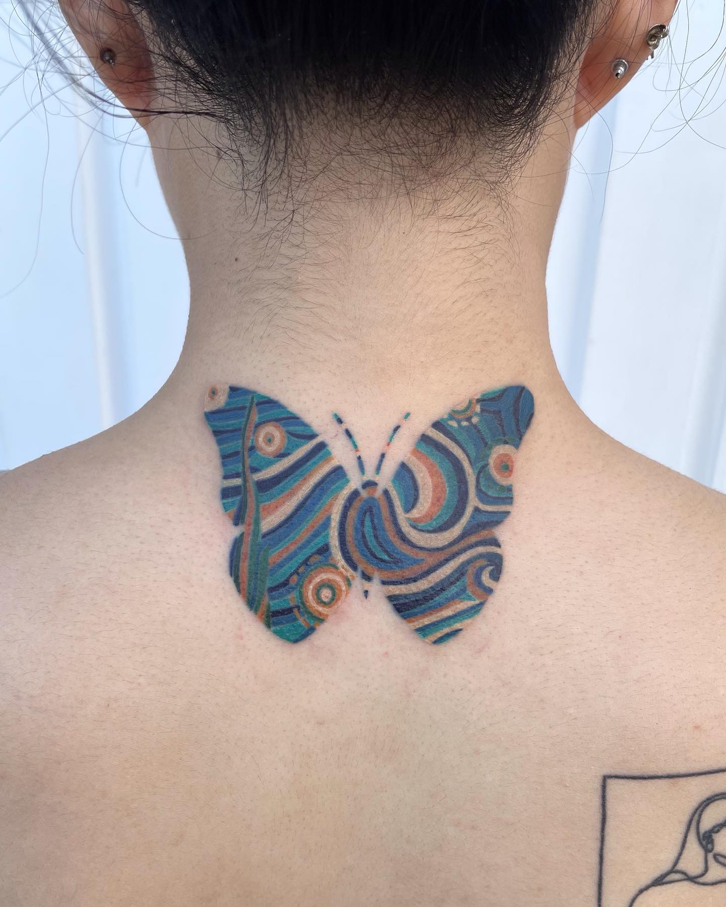 Diseño de mariposa tatuada en el cuello en azul.