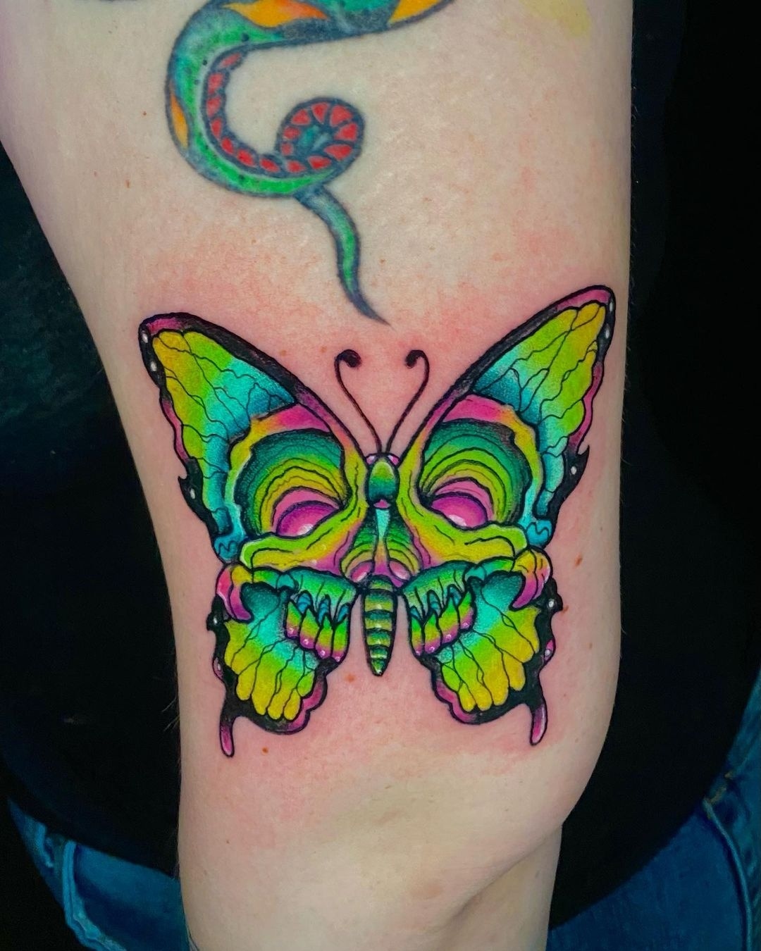 Tatuaje brillante de mariposa de neón.