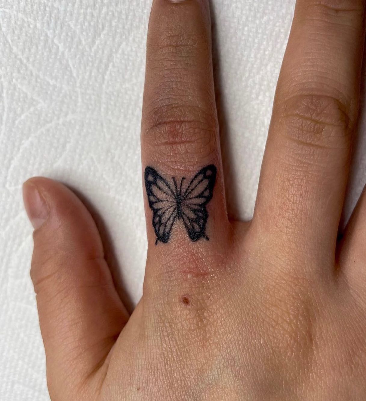 Tatuaje de mariposa minimalista en el dedo
