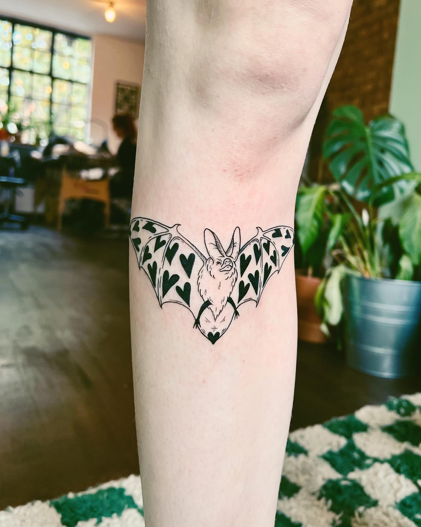 Tatuaje de murciélago con símbolos de corazón.