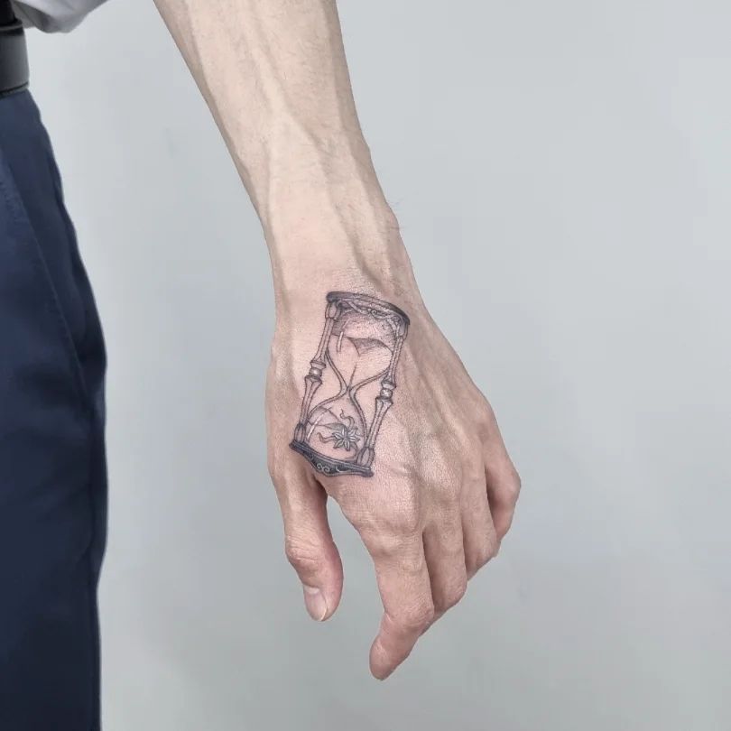 Diseño de tatuaje de reloj de arena en el brazo.