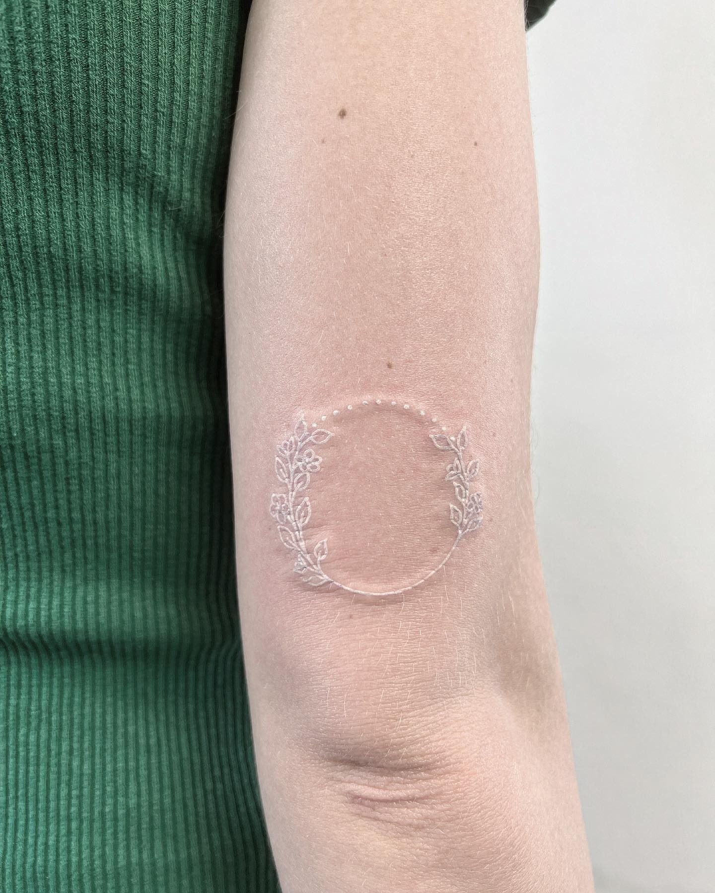 Tatuaje circular de tinta blanca.