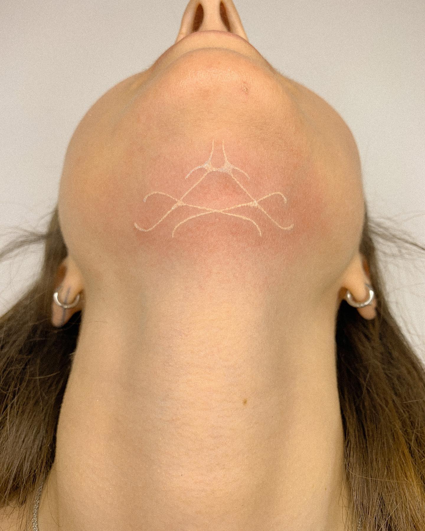 Tatuaje de tinta blanca en el cuello