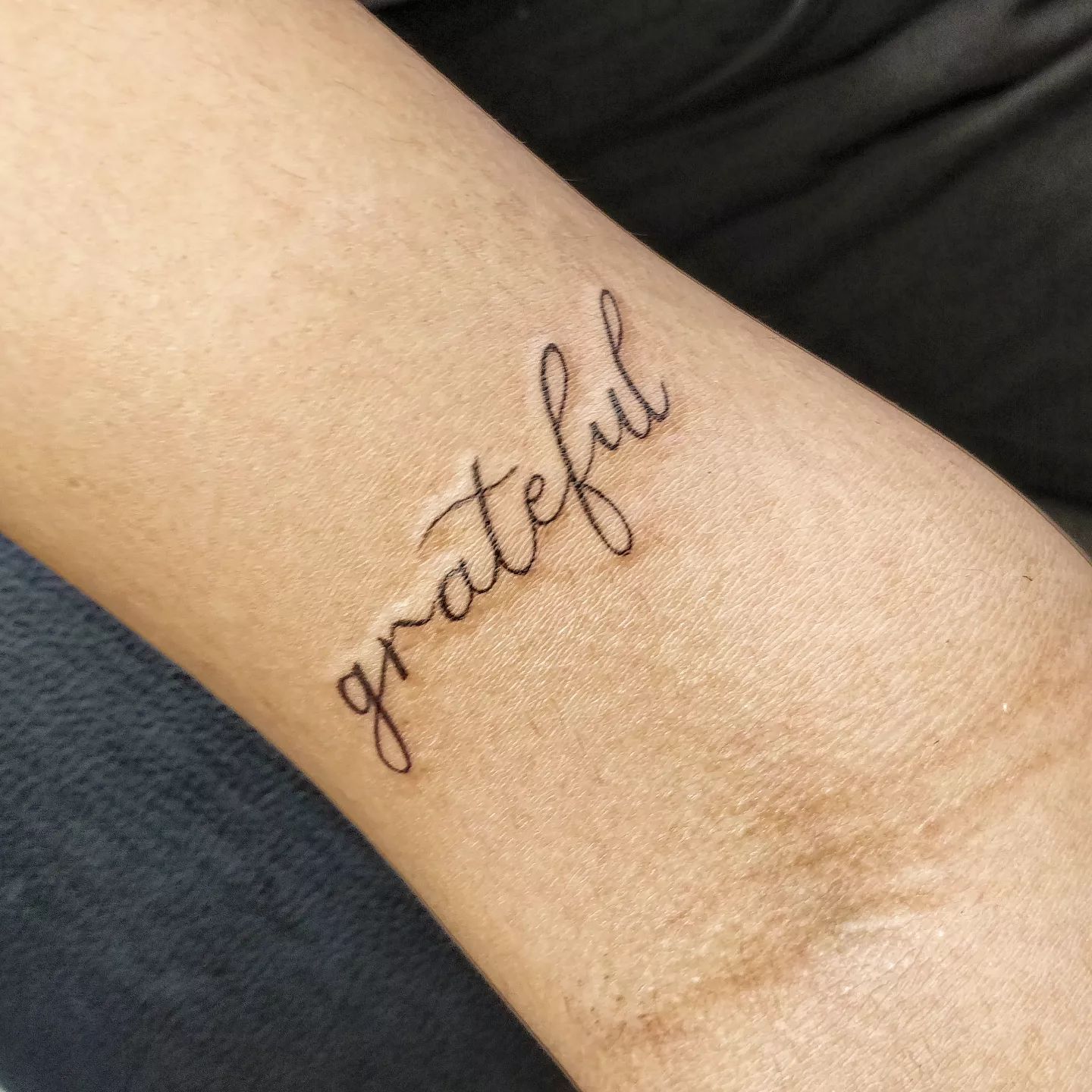 Tatuaje agradecido de una sola palabra.