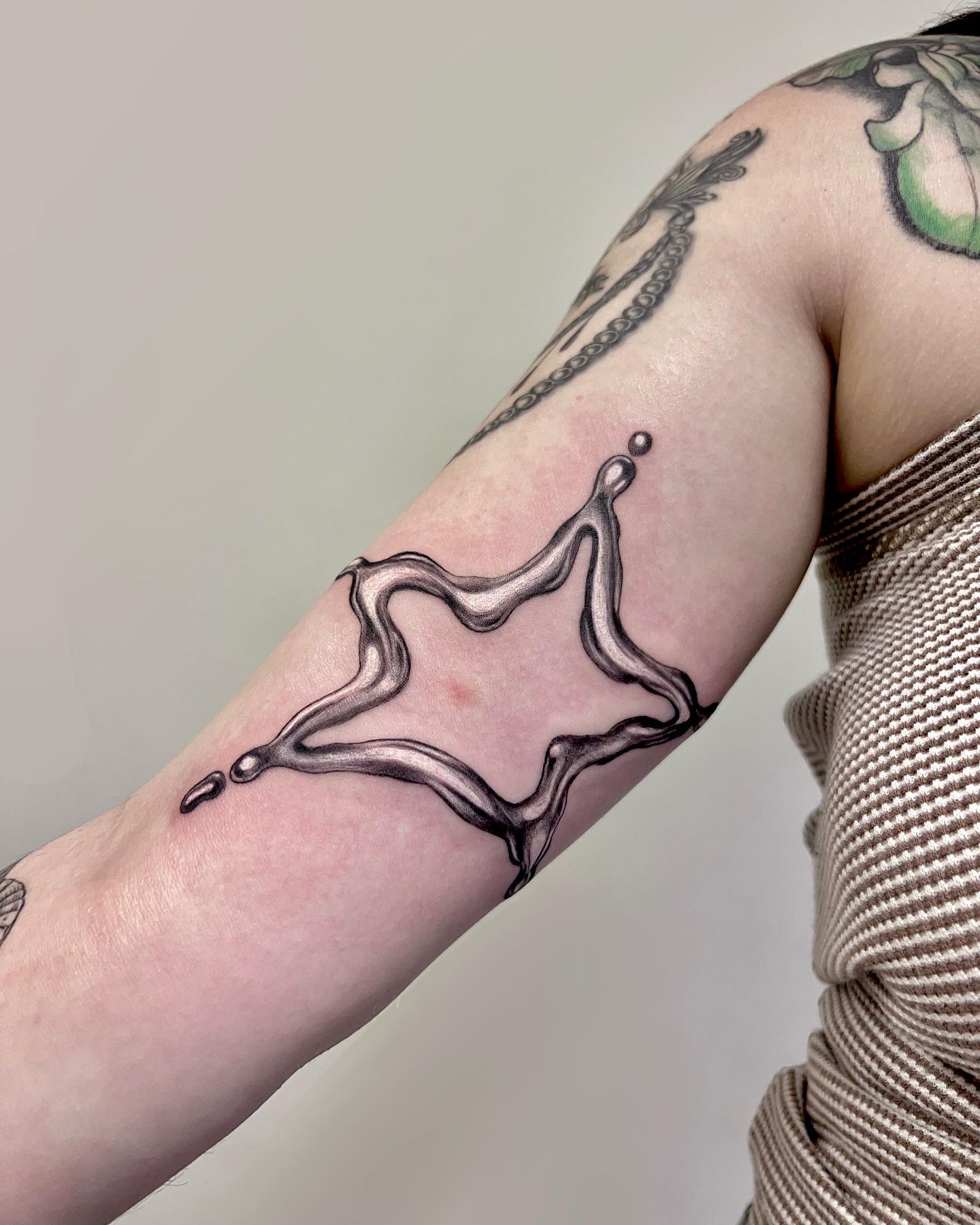 Tatuaje de contorno de estrella líquida en el brazo.