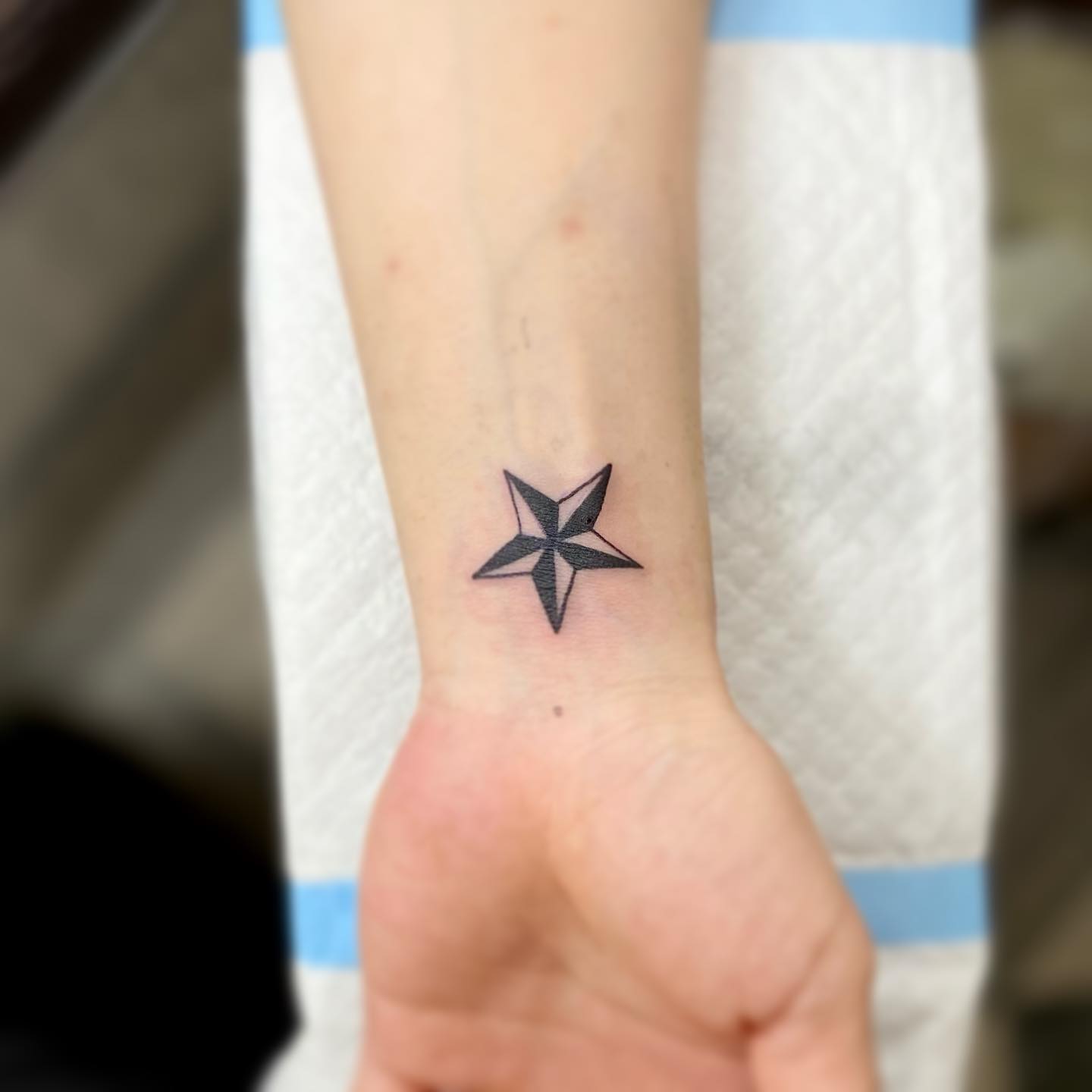 Tatuaje de estrella náutica en la muñeca