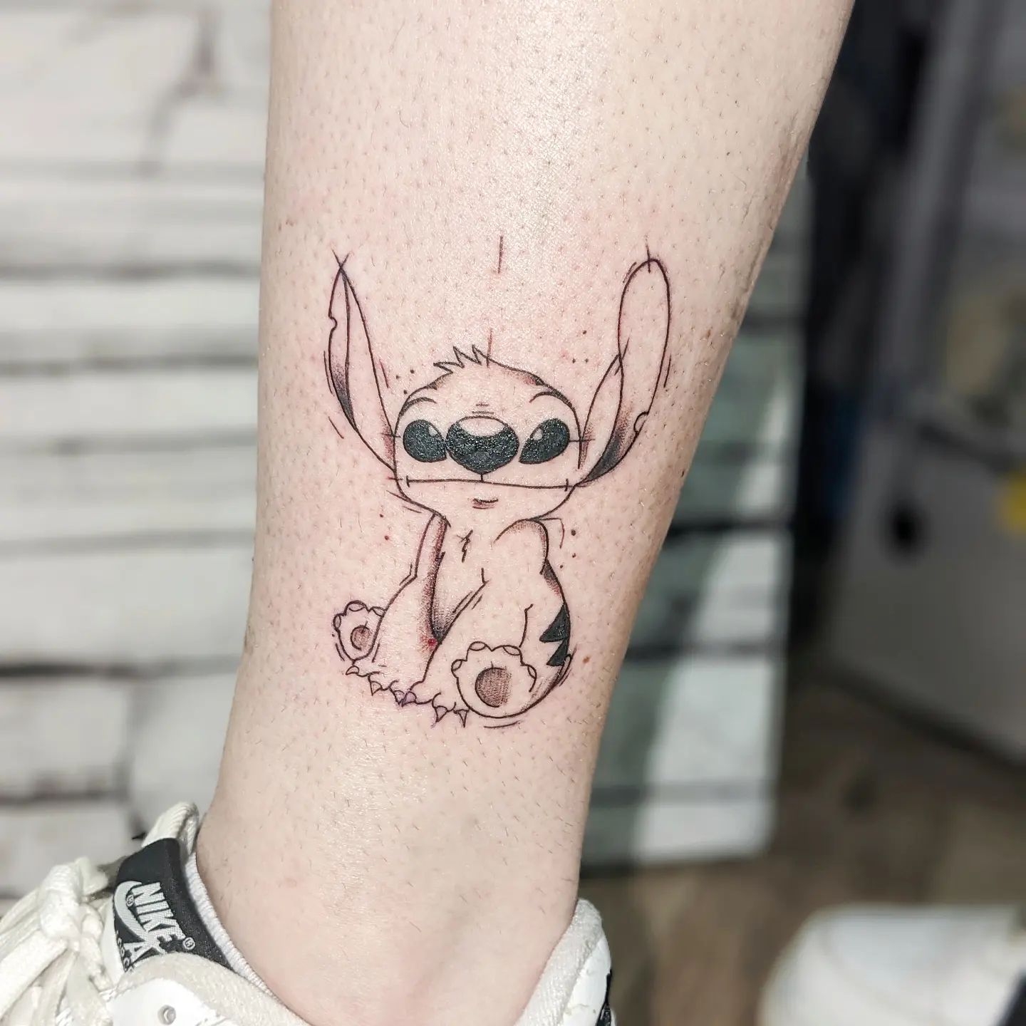 Tatuaje de Stitch con tinta negra.