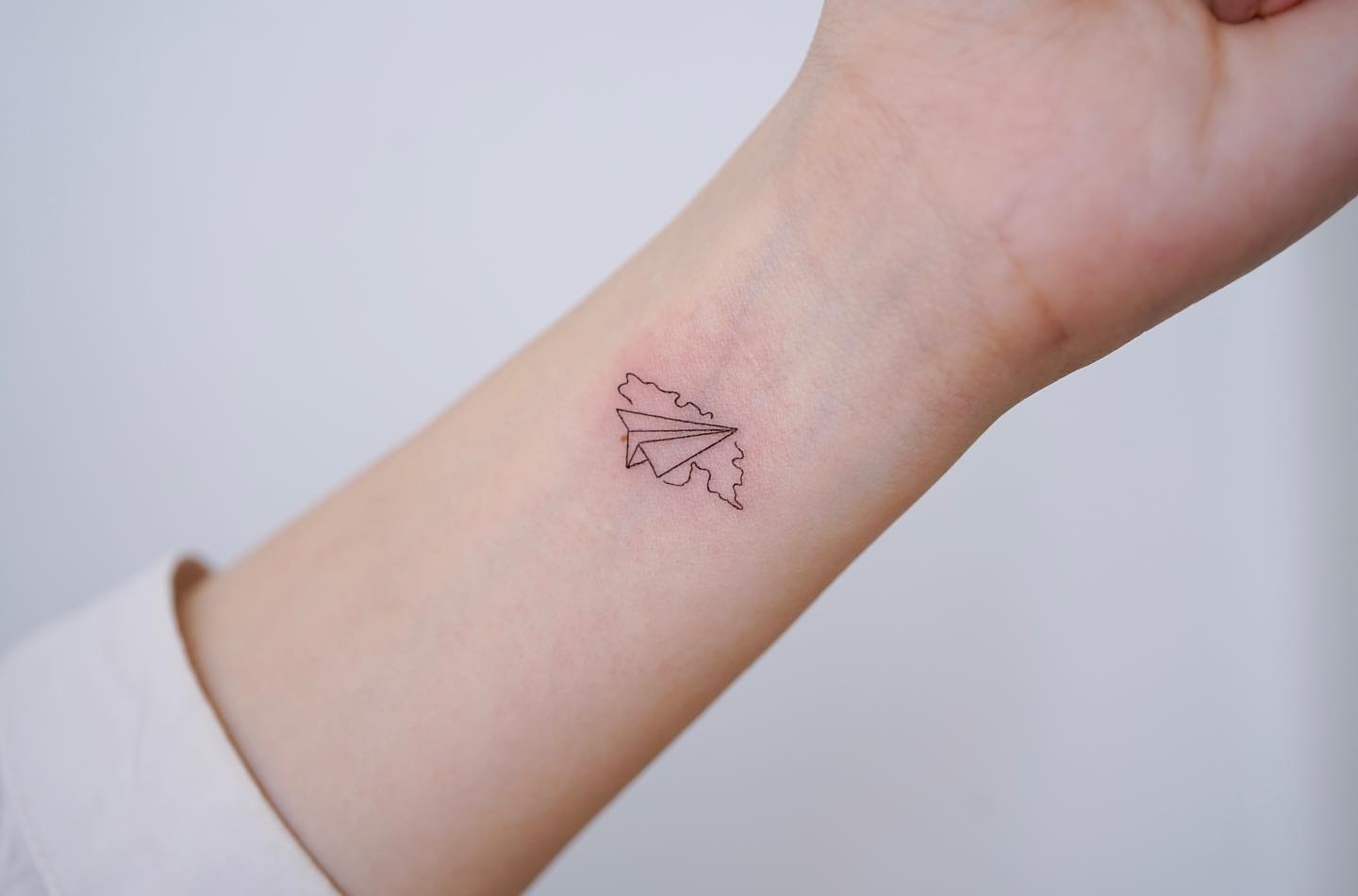 Tatuaje de pequeño avión de papel azul.