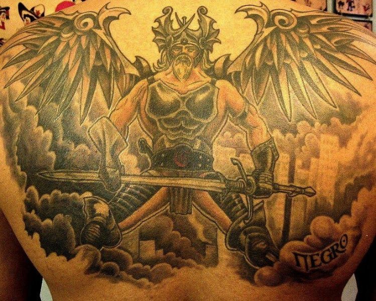 Los tatuajes de guerrero suelen ir acompañados de otros motivos guerreros y fantásticos. En este caso todo un fondo de nubes en el que se puede distinguir una ciudad al fondo. Todo tatuado en la espalda.